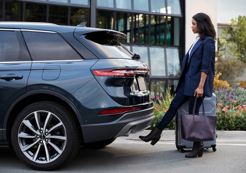 A woman with luggage and a bag opens the available hands-free liftgate by kicking her foot under the bumper | Pierre Lincoln in Lynnwood WA