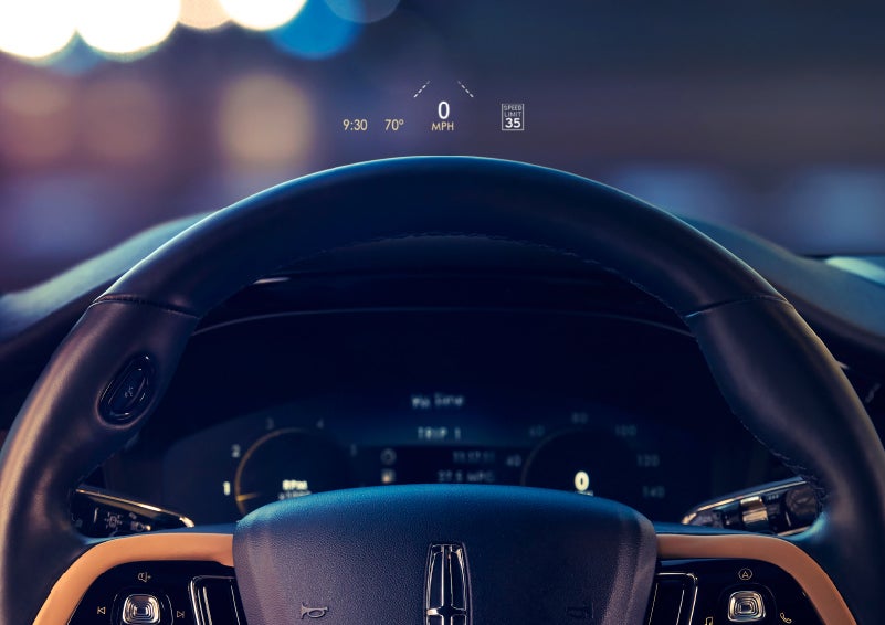 The available head-up display projects data on the windshield above the steering wheel inside a 2022 Lincoln Corsair as the driver navigates the city at night | Pierre Lincoln in Lynnwood WA