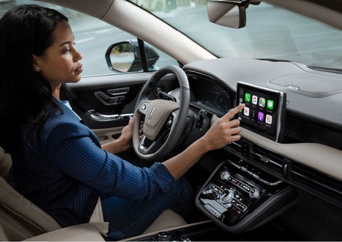A woman in the driver’s seat of a 2022 Lincoln Corsair is touching the center digital screen to connect to Apple CarPlay<sup>®</sup> | Pierre Lincoln in Lynnwood WA