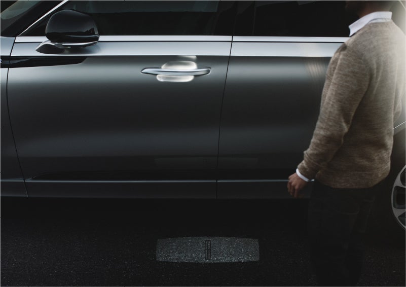 A person approaches a 2023 Lincoln Aviator® Grand Touring SUV as the Lincoln Embrace sequence of welcome lighting illuminates | Pierre Lincoln in Lynnwood WA