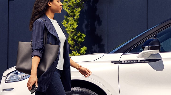 A woman approaches a 2024 Lincoln Corsair® SUV while holding a smartphone. | Pierre Lincoln in Lynnwood WA