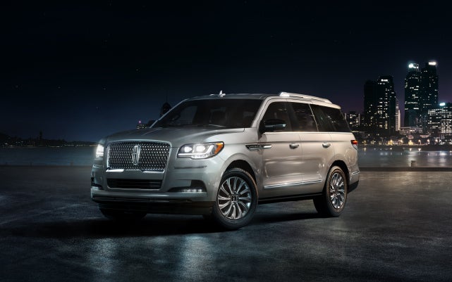 A 2024 Lincoln Navigator® SUV is parked near a city's riverside walk at night
